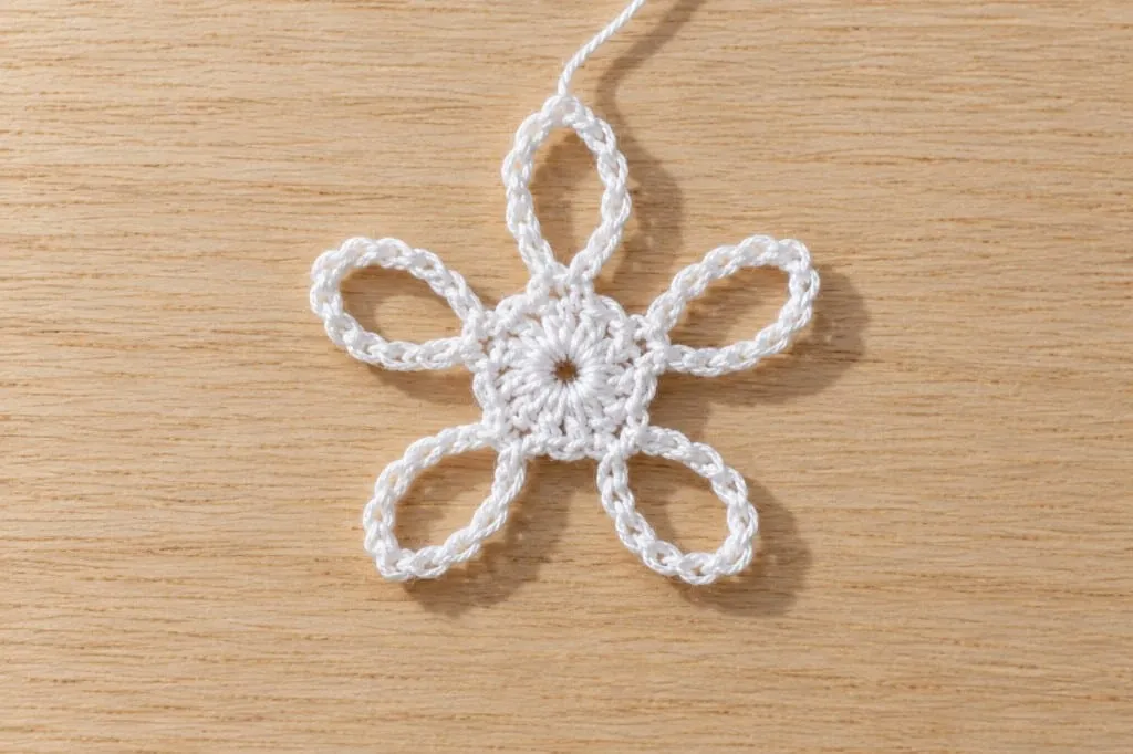 A white thread motif with five chain-loop petals radiating from a closed center ring